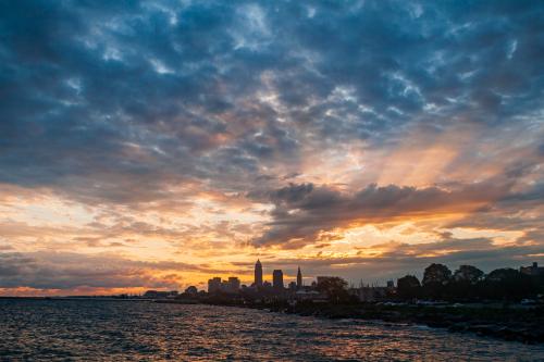 A dramatic sky with crepuscular rays spreading across it with the Cleveland skyline in silhouette in the foreground.